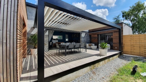 un espace convivial sous une pergola bioclimatique adossée